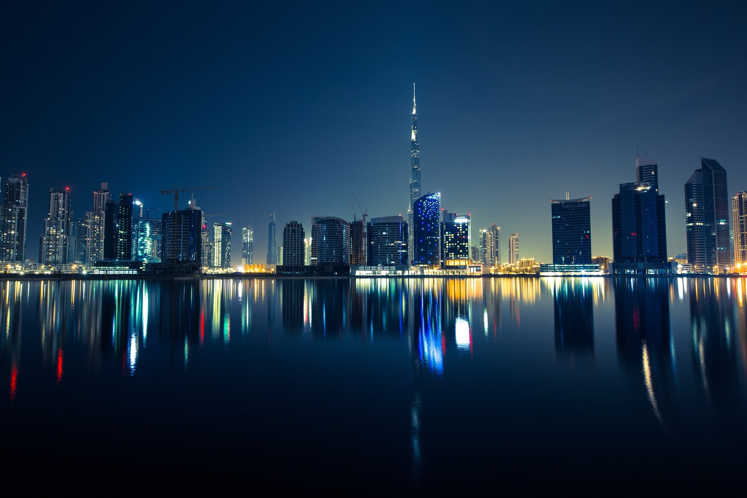 Dubai skyline at blue hour with the Burj Khalifa and Business Bay towers reflected in the water